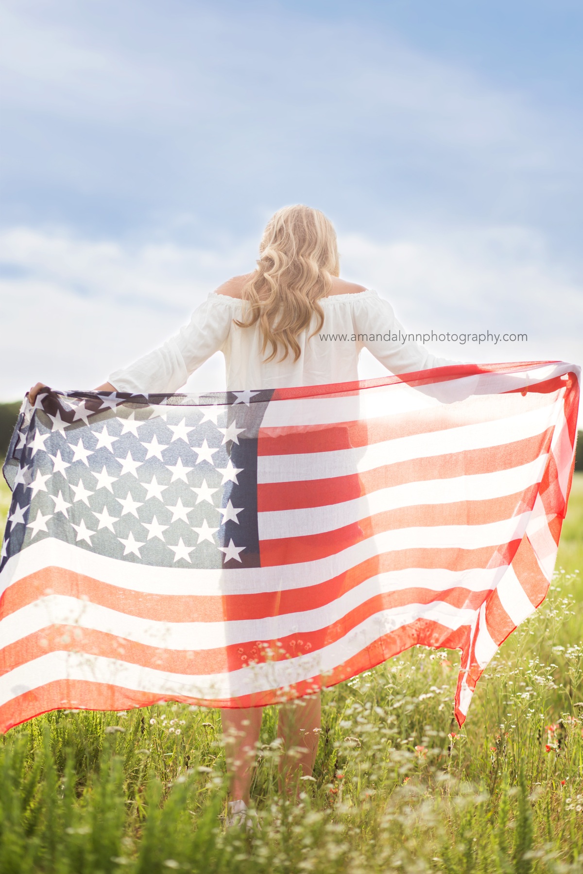 2017 Senior Rep for Amanda Lynn Photography walking through a field of flowers with the american flag in the oklahoma city area